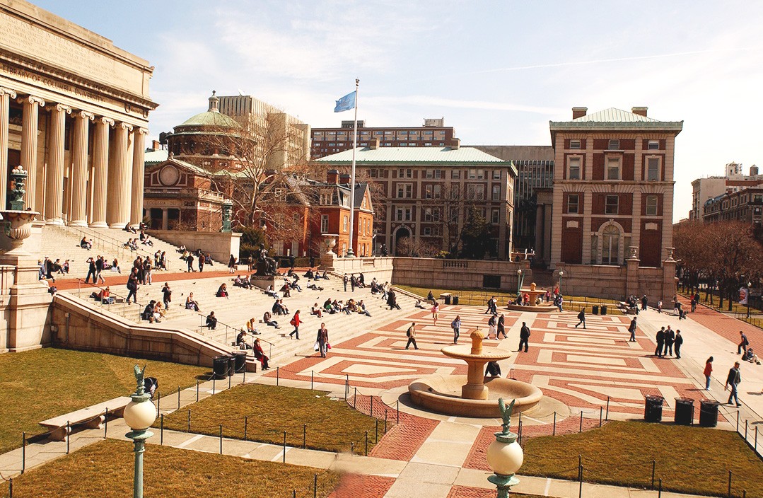 Columbia Campus photo in front of low library. Students sitting on the steps, and walking around a nice, bright day.
